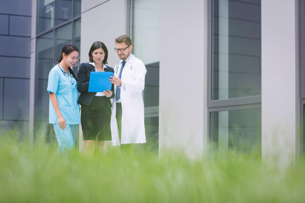 Healthcare professionals consulting with legal advisor outside medical facility