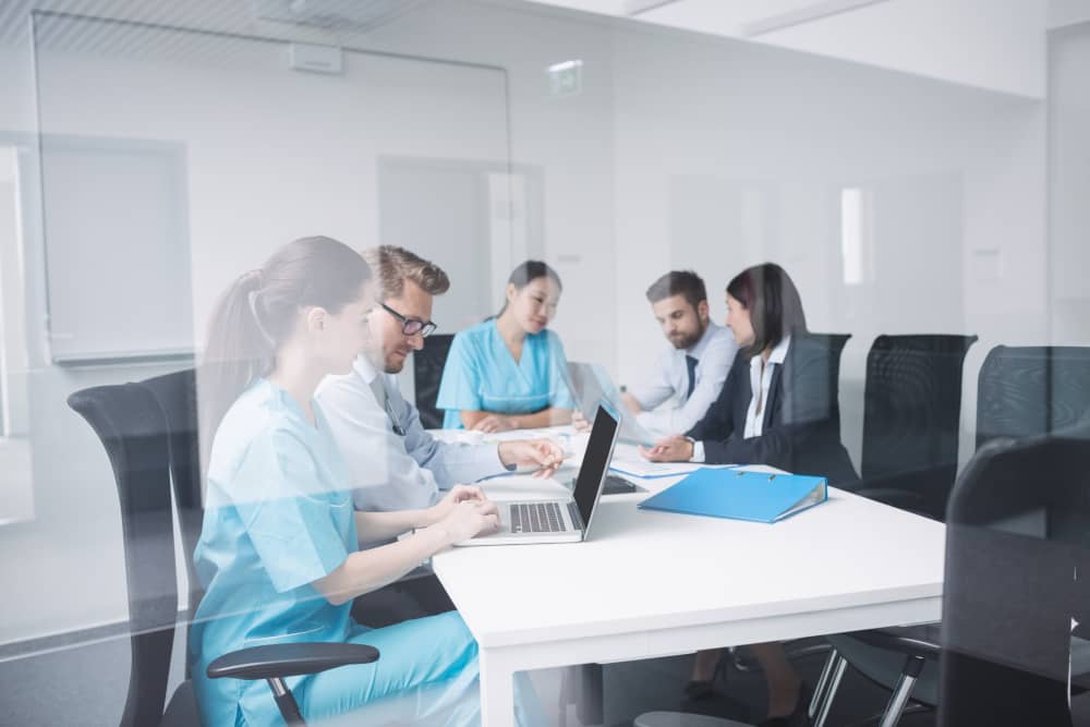 Healthcare professionals in scrubs and business attire discussing business formation documents in modern conference room