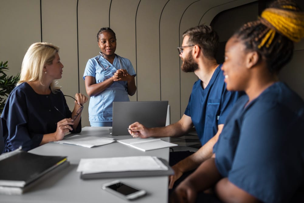 Healthcare team meeting with diverse medical staff discussing protocols around a conference table