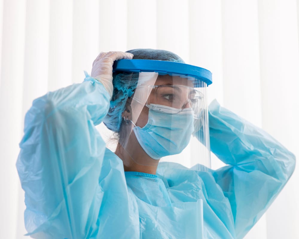 Healthcare worker adjusting face shield and PPE