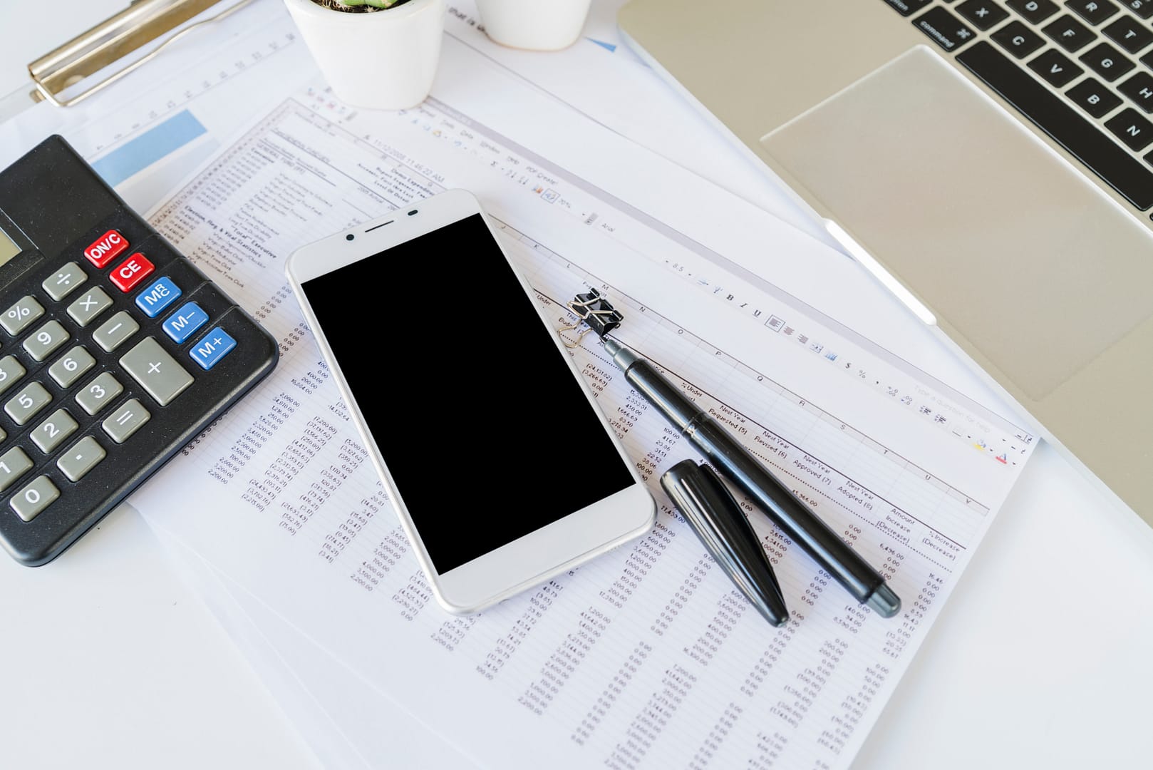 Tax documents, calculator, and laptop on desk showing business financial planning materials
