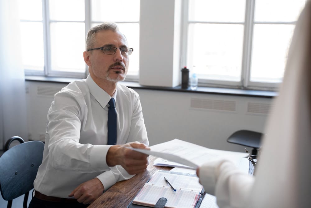 Professional attorney in white shirt and tie reviewing legal documents at desk in modern office