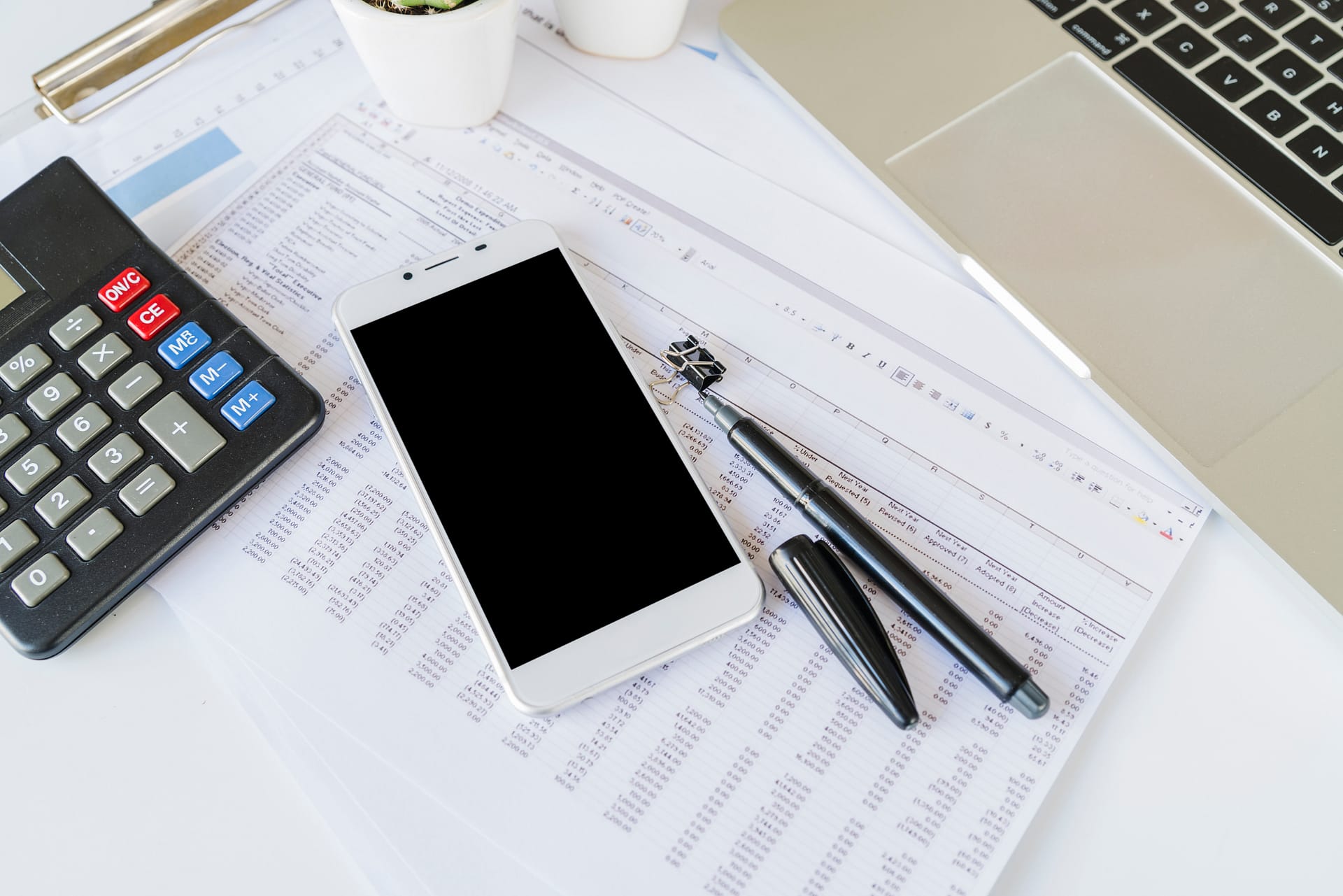 Tax documents, calculator, and laptop on desk showing business financial planning materials