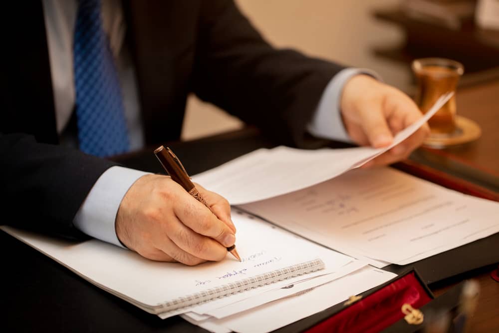 Business professional signing legal contracts with pen at wooden desk